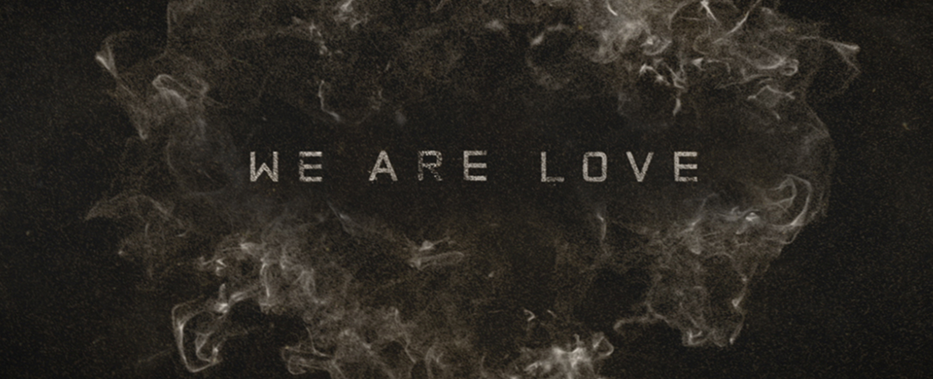 We Are Love title in smoke and dust on dark background